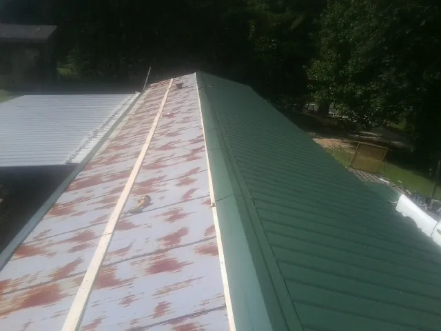 Old rusted panels beside newly installed green metal roofing — Wind Damage Roof Repair by Roofing Brothers in Ceresco