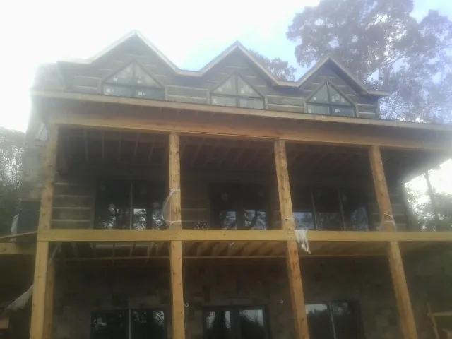 Dormers and porch framing on a large log home under construction — Roof Coating work by our crew in Ceresco