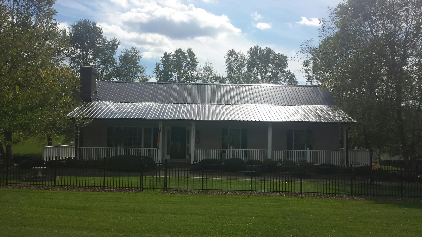 Gray metal roof on a brick ranch with a full width front porch — Gutter Guard Installation work by our crew in Ceresco
