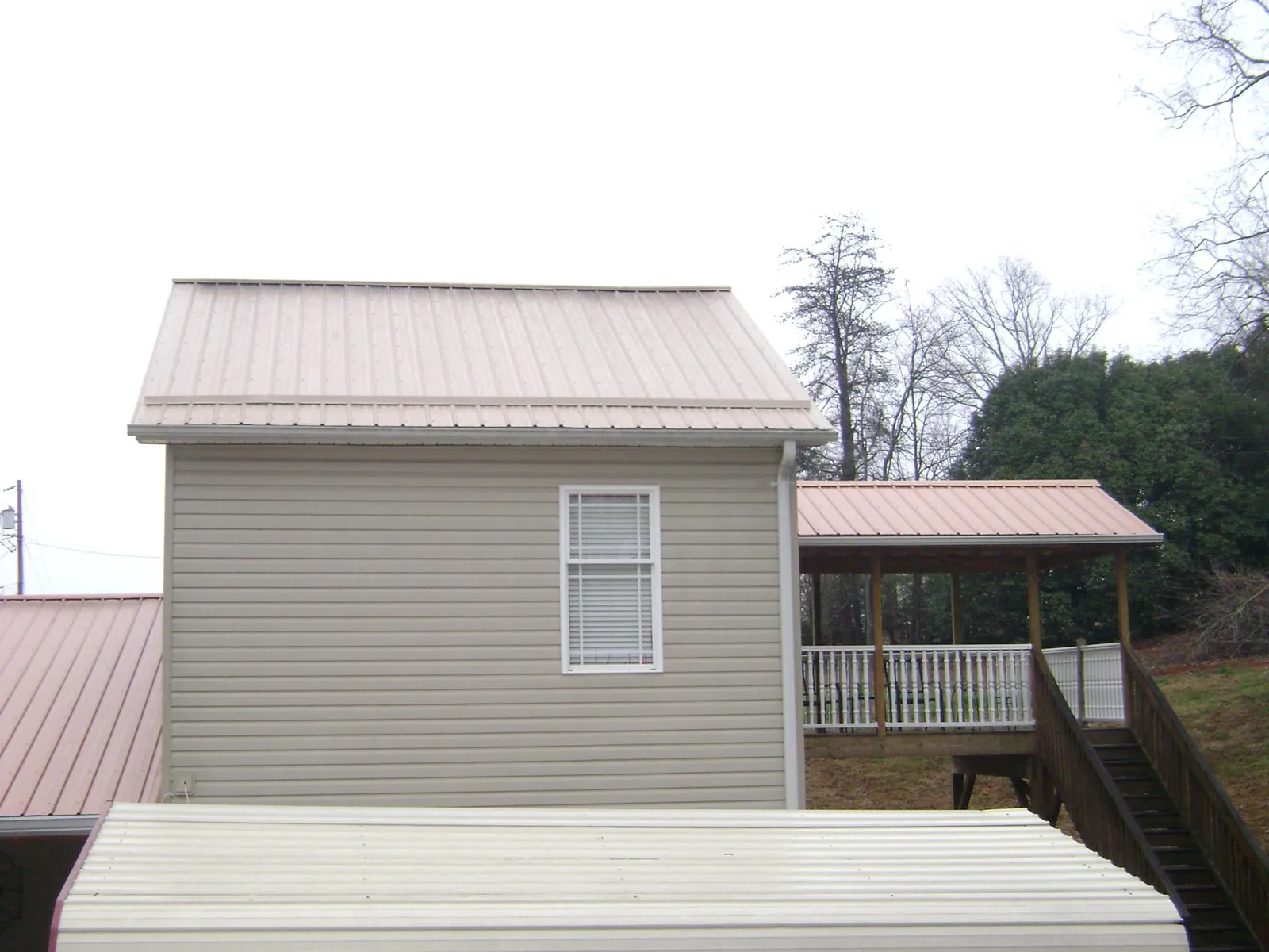 Tan metal roofs on a two story addition and attached porch, from a Roof Replacement job in Ceresco