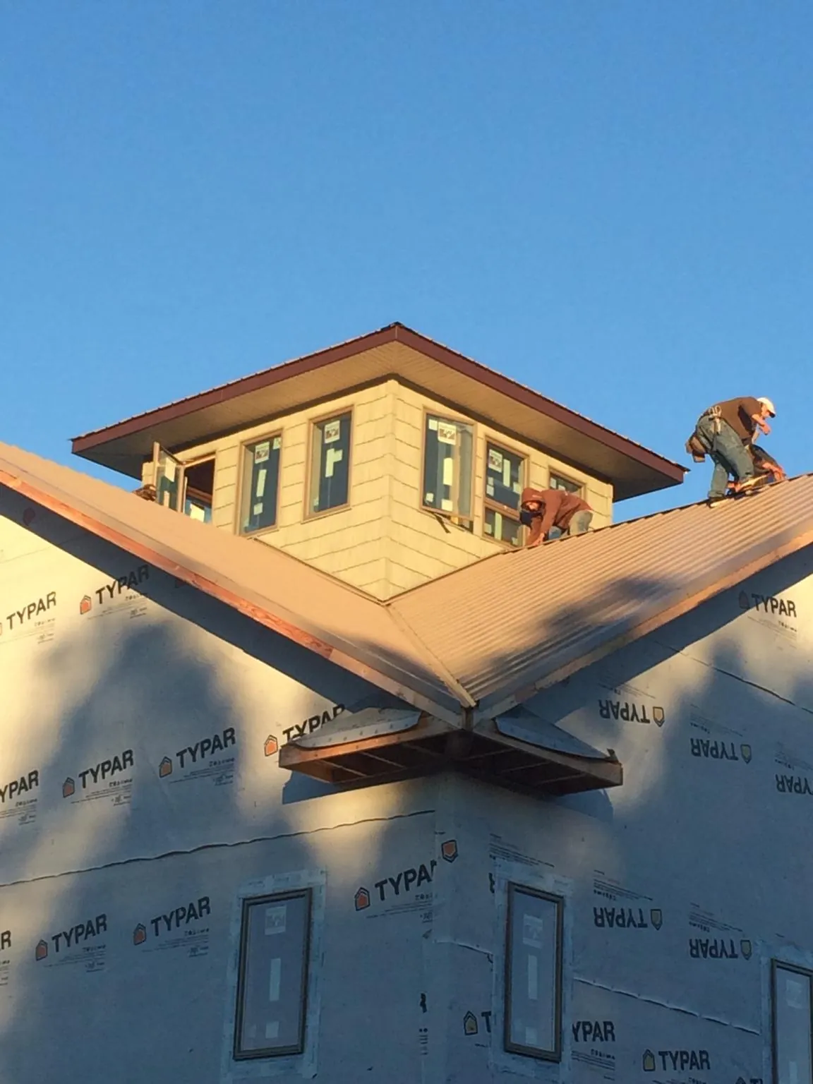 Roofers working around a rooftop cupola on a new metal roof at sunset — Roof Waterproofing in Ceresco by Roofing Brothers